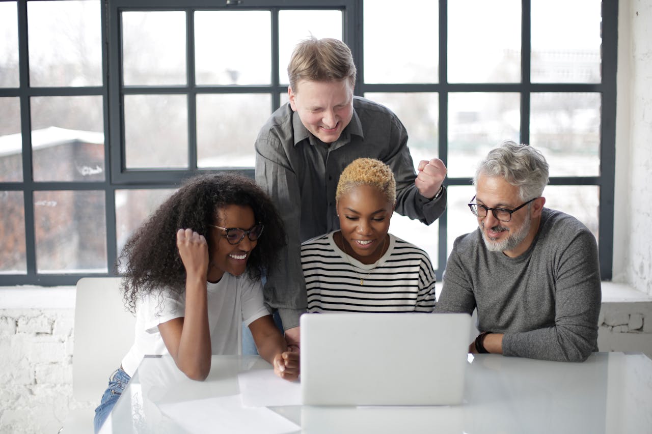 A diverse group of colleagues happily collaborating on a project in a bright, modern office environment.